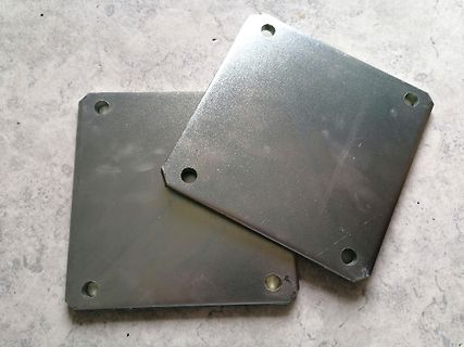 Zwei quadratische Metallplatten mit Bohrungen