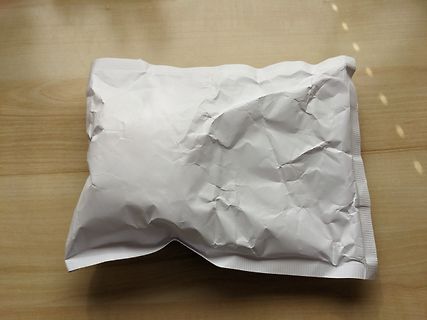 Weiße, zerknitterte Verpackung auf Holztisch