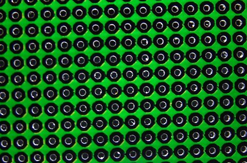 Makroaufnahme einer Matrix aus schwarzen Punkten auf grünem Grund
