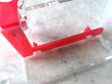 Rote Kunststoffhalterung in transparentem Gehäuse