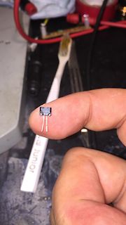 Hand hält ein kleines elektronisches Bauteil