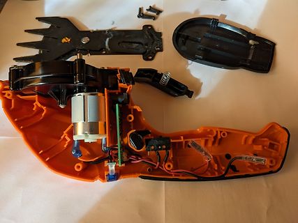 Zerlegtes orangefarbenes Elektrogerät mit Motor und Platine