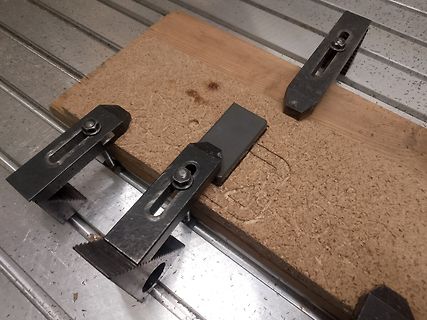 Holzbrett mit Schraubzwingen auf Metalltisch