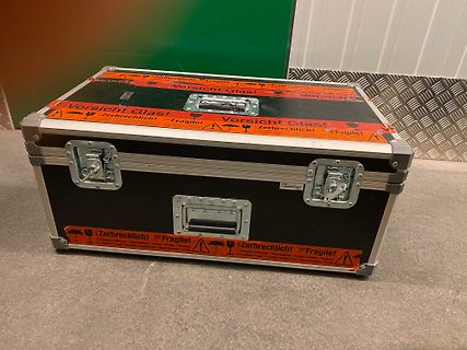 Schwarzer Transportkoffer mit Warnaufklebern