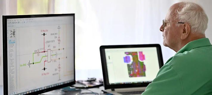 Mann betrachtet Schaltplan und PCB-Layout am Monitor