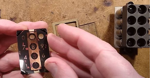 Hände halten eine kleine Platine mit Ziffern