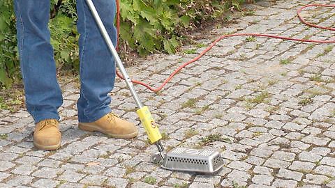 Person mit Lecksuchgerät auf Pflastersteinen