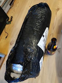 Paket in schwarzer Plastikfolie auf Holzboden