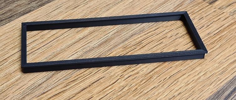 Schwarzer 3D-gedruckter Rahmen auf Holzuntergrund