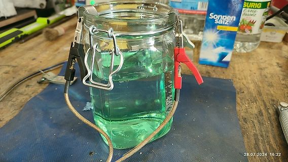 Glasgefäß mit grüner Flüssigkeit auf Werkstattunterlage