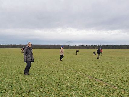 Personen auf einem Feld unter bewölktem Himmel
