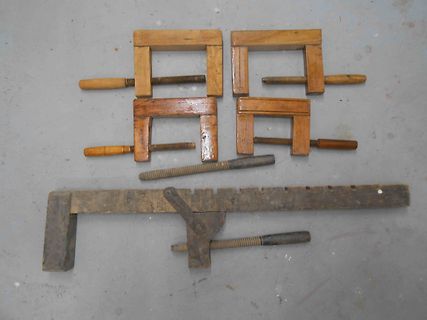 Holzschraubzwingen und eine Metallzwinge auf grauem Grund