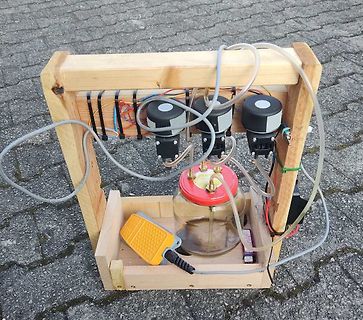 Experimenteller Aufbau mit Pumpen und Glasgefäß auf Holzrahmen