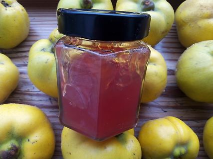 Glas mit roter Marmelade und Quitten