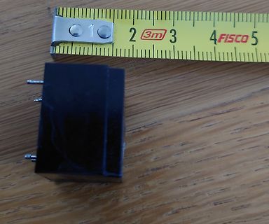 Schwarzes Bauteil neben einem Maßband