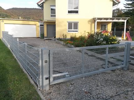 Haus mit Garagenzufahrt und Metallzaun