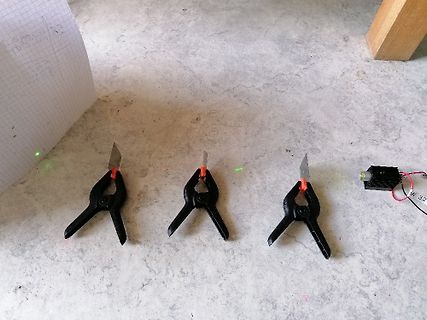 Drei Krokodilklemmen und ein Bauteil auf Tischplatte