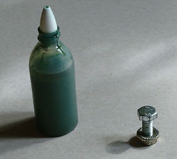 Flasche mit grüner Flüssigkeit und Schraube