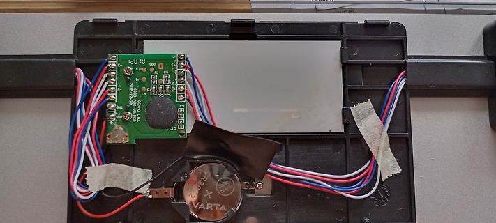 Geöffnetes Elektronikgehäuse mit Platine und Knopfzellenbatterie