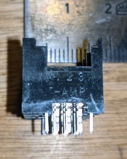 Elektronikbauteil mit Metallstiften vor Lineal