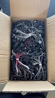 Karton voller grauer Flachbandkabel mit Steckern