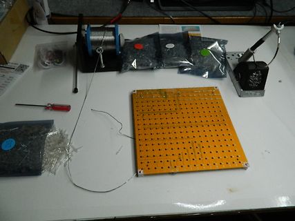 Werkstatt mit Lochrasterplatine, Lötdraht und Werkzeug