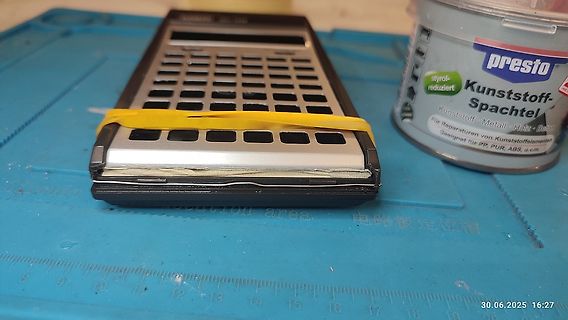 Taschenrechner und Spachtelmasse auf Werkstattunterlage