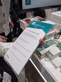 Hand hält Infineon Flyer auf Messe
