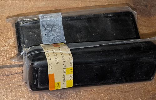 Zwei schwarze Bauteile in Plastikverpackung
