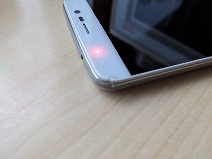 Smartphone mit leuchtender LED-Anzeige auf Holztisch