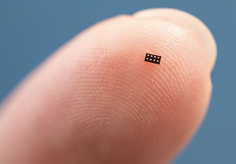 Mikroskopische Aufnahme eines winzigen elektronischen Bauteils auf einer Fingerspitze
