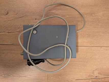 Graues Gehäuse mit Netzkabel auf Holzboden