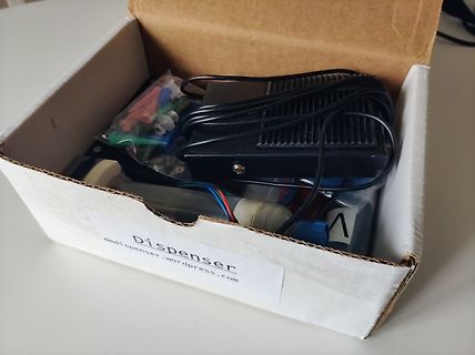 Inhalt eines Kartons mit Elektronikkomponenten und Netzteil