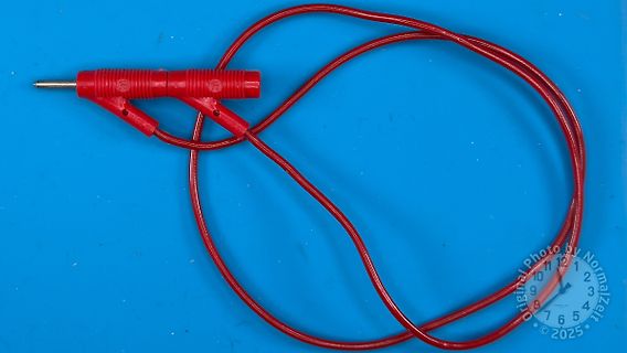 Rote Messklemme mit Kabel auf blauem Grund