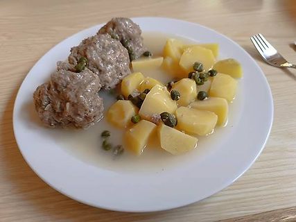 Fleischklößchen mit Kartoffeln und Kapern auf weißem Teller