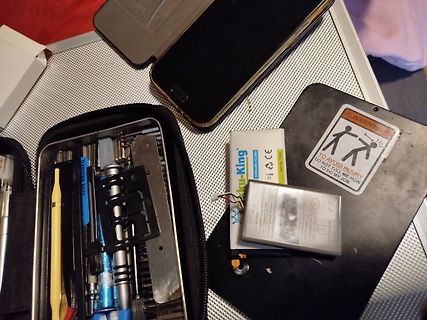 Werkzeugset, Smartphone und Akkus auf Tisch