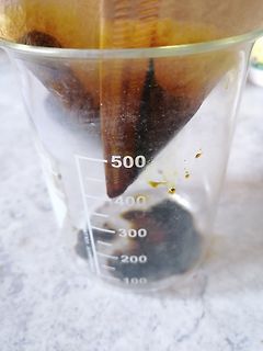Becherglas mit dunkler Flüssigkeit und Ablagerungen