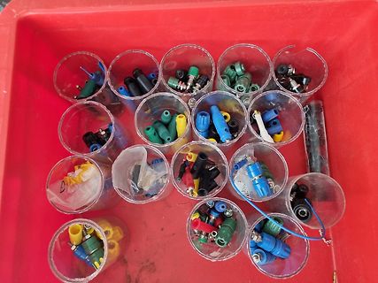 Mehrere Becher mit bunten Steckverbindern und Kabeln