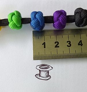 Bunte Paracord-Armbandknoten neben einem Lineal