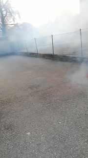 Draufsicht auf einen asphaltierten Platz mit Zaun und Nebel