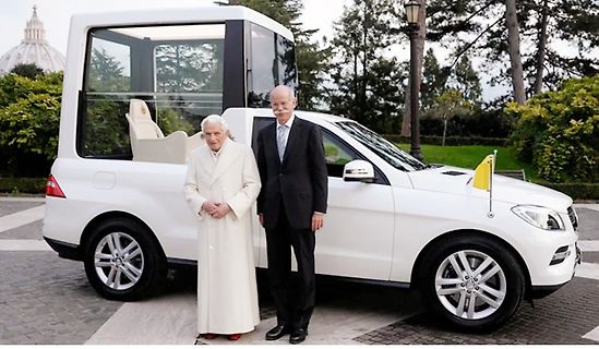 Papst Franziskus und ein Mann neben einem weißen Fahrzeug