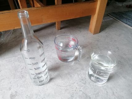 Messbecher und Flasche mit Wasser