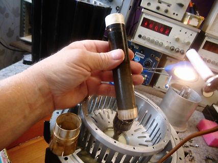 Hand hält Bauteil über Elektromotor