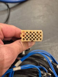 Hand hält beige Steckverbindung mit blauen Kabeln
