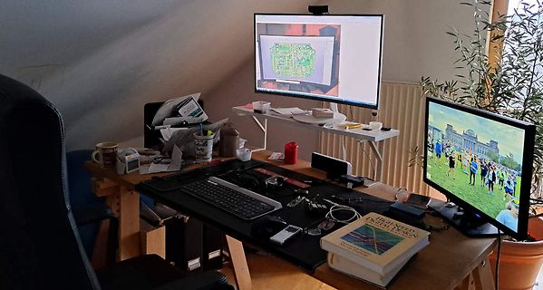 Arbeitsplatz mit Monitoren, Tastatur und Fachbuch