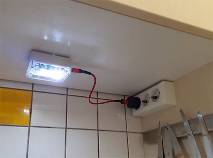 Geöffnetes Leuchtmittel an Steckdose mit rotem Kabel