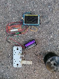 Elektronik-Aufbau mit Display, Batterien und Platine auf Asphalt