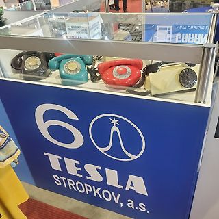 Retro-Telefone in einer Vitrine vor Tesla-Logo