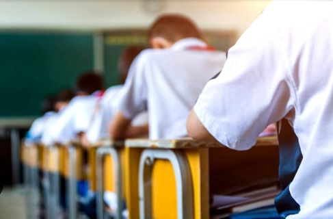 Schüler sitzen an Schreibtischen im Klassenzimmer