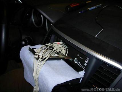 Ausgebautes Autoradio mit Kabelbaum im Fahrzeuginnenraum